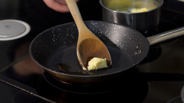 person melting butter in skillet