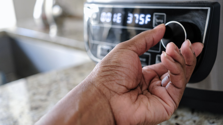 person adjusting air fryer temperature