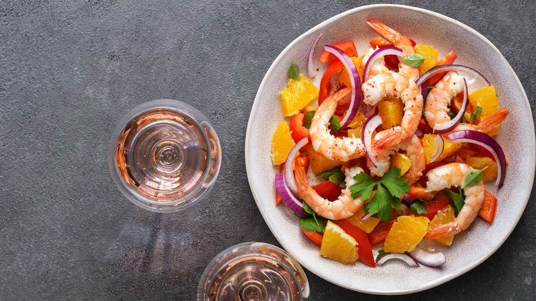 Bowl of shrimp salad with wine glasses