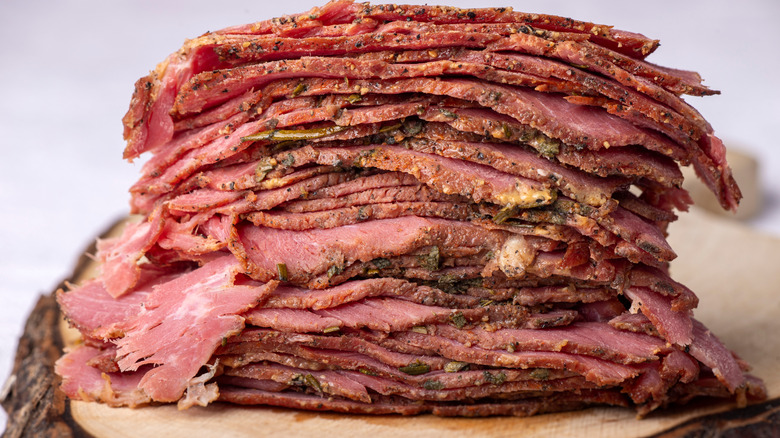 Pastrami slices stacked on board