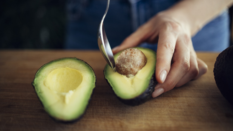 person removing stone from avocado