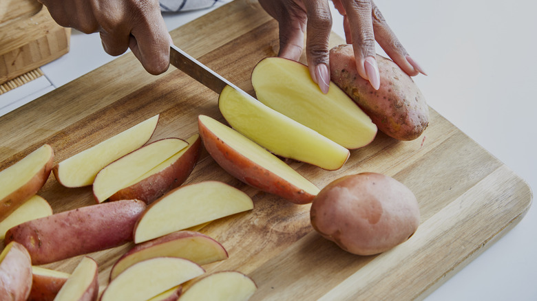 Person slicing potatoes on board