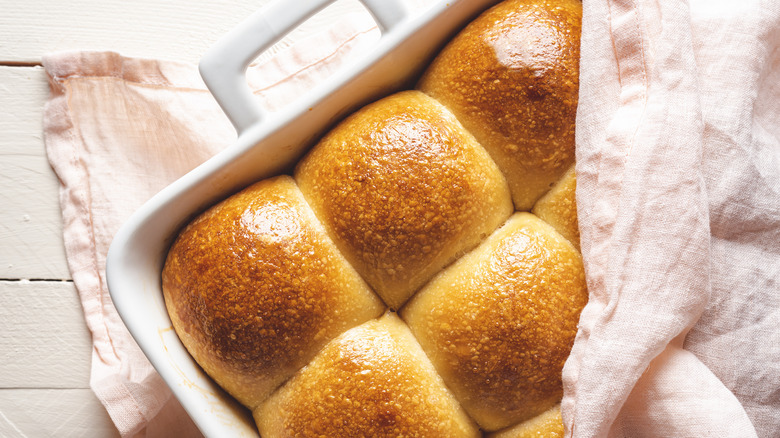 fresh baked rolls iin dish covered with cloth