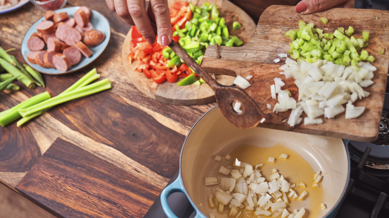 person putting vegetables into pot