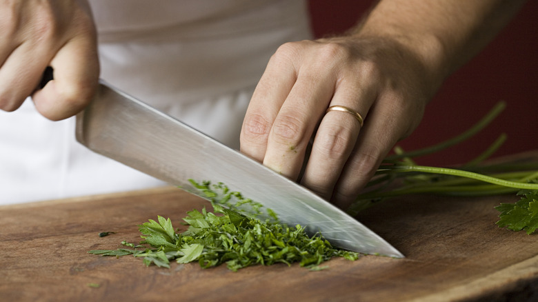 person slicing herbs on wood