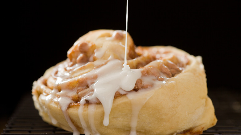 pouring icing on cinnamon roll