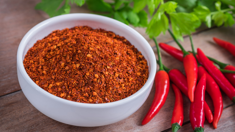 Bowl of cayenne pepper with red chilies next to it