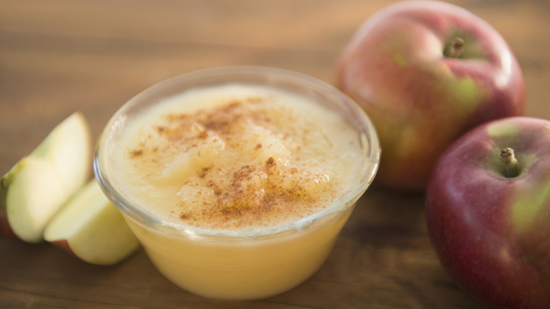 Bowl of cinnamon-spiced applesauce, surrounded by apples