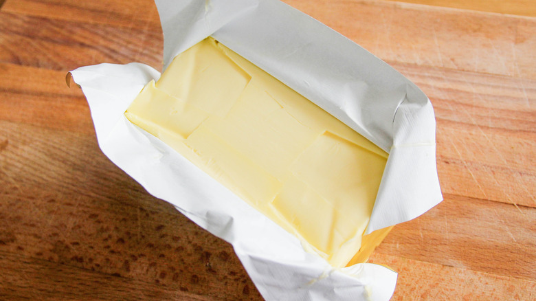 Open stick of butter on wooden surface