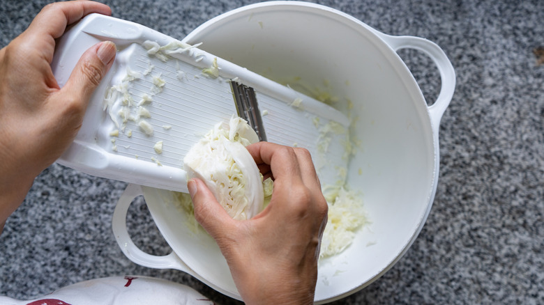 person cutting cabbage with mandoline