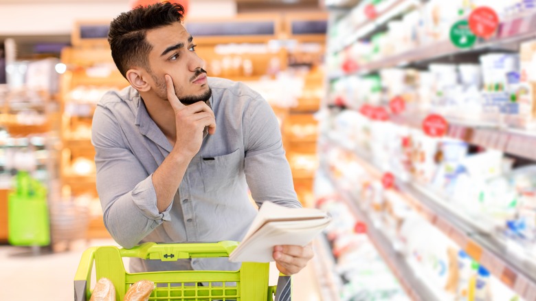 man holding grocery list and shopping