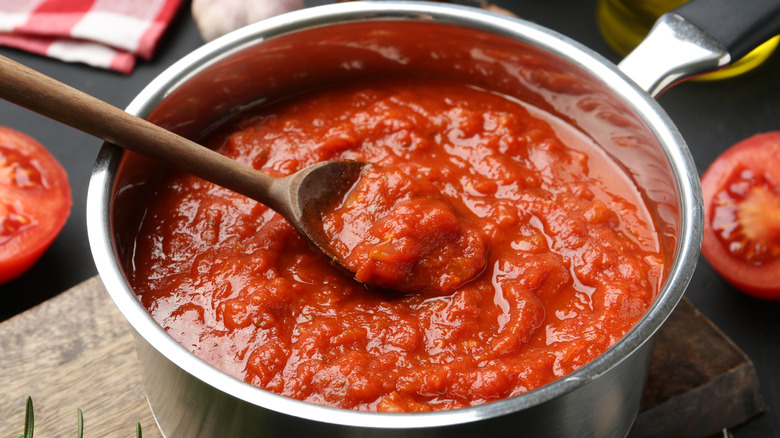 Spoonful of tomato sauce resting on top of sauce in a pan