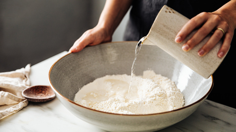 woman pouring water into flour