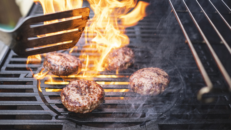 burgers being grilled over flame