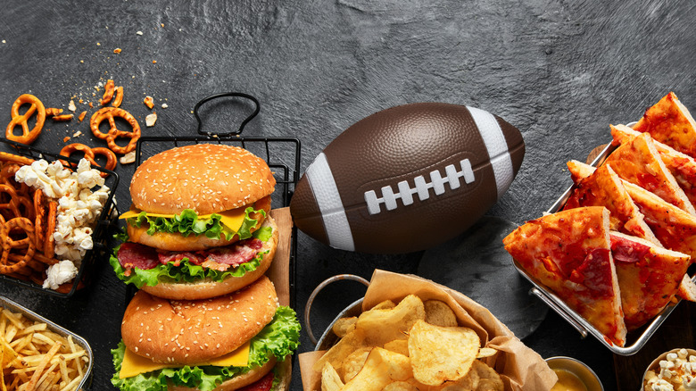 A football with various snacks, including burgers, pizza, chips, popcorn, and pretzels