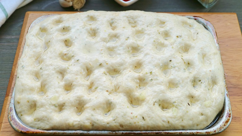 Dimpled focaccia dough in pan