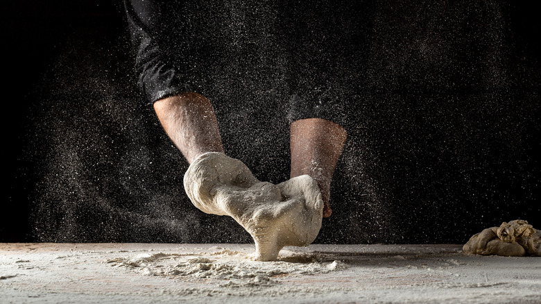 Hands working dough with flour