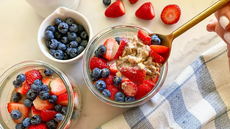 Top-down view of oatmeal, blueberries, and strawberries in glass jars