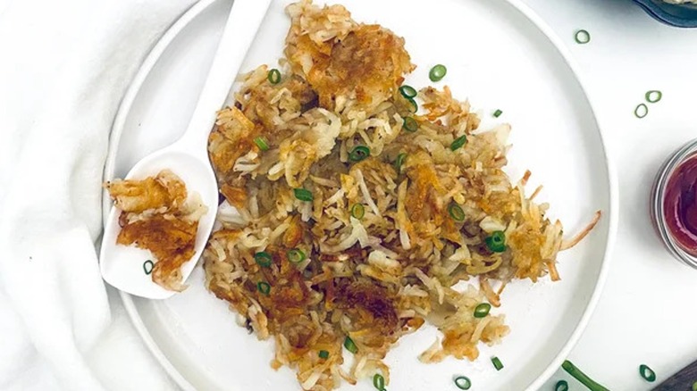 Top-down view of hash browns on a white plate