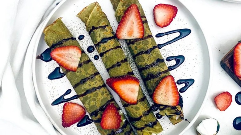 Top-down view of matcha pancakes and strawberries on a plate