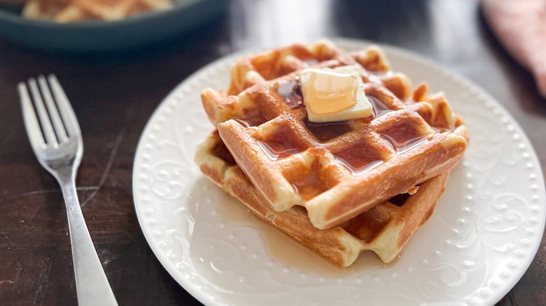 Waffles and butter on a plate with a fork