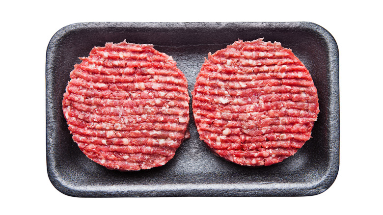 Raw burger patties in tray