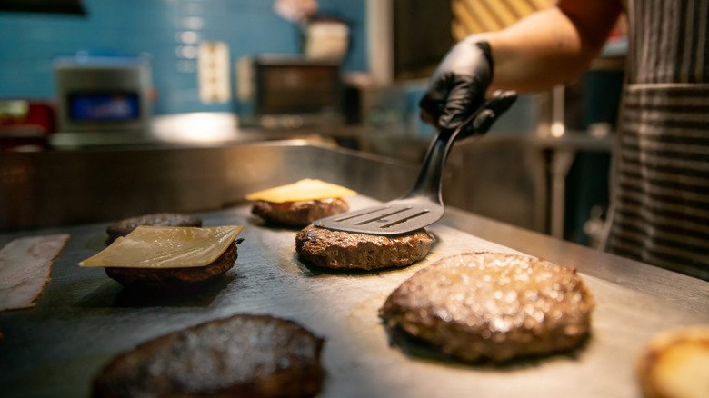 chef cooking burgers on grill