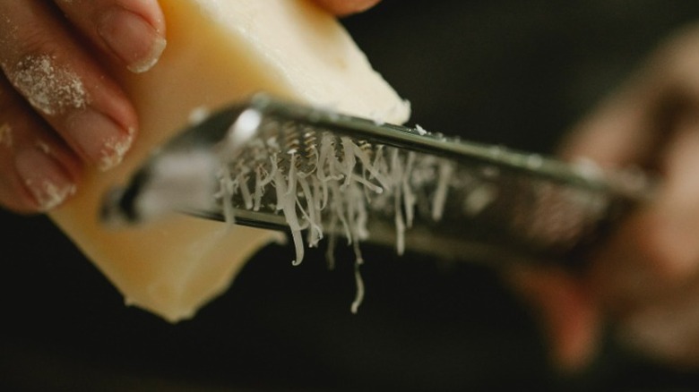 Hands grating cheese close up