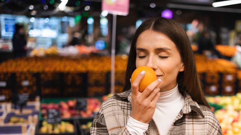 woman smelling oranges at store