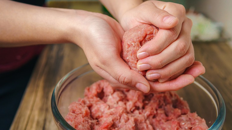 Hands mixing ground meat