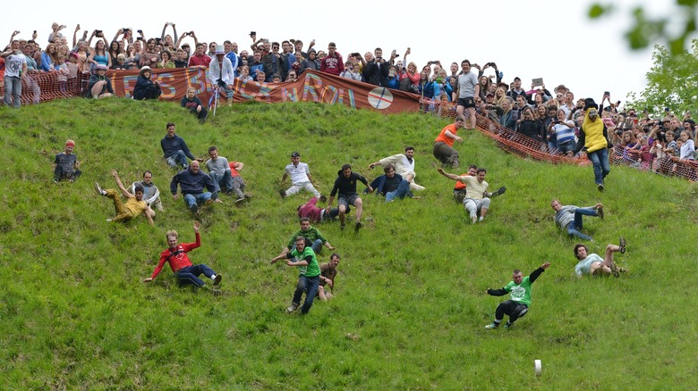 spectators watch people rolling downhill