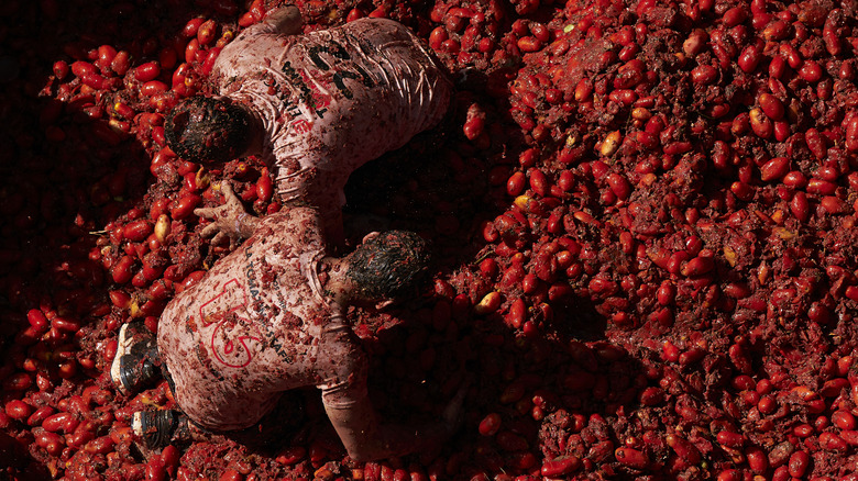 men in pile of tomatoes