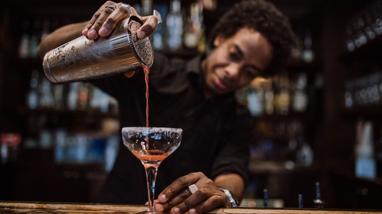 bartender pouring cocktail into glass