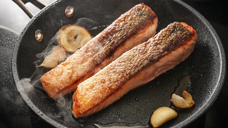 fish cooking in pan with skin on