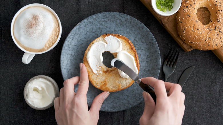 Cream cheese being spread on bagel