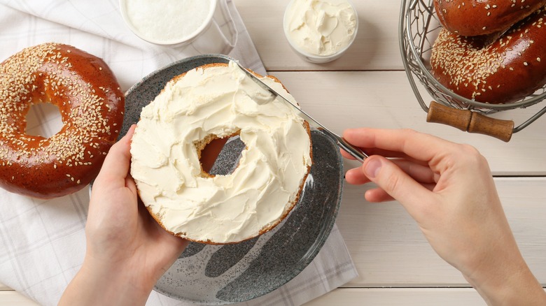 Bagel being spread with cream cheese