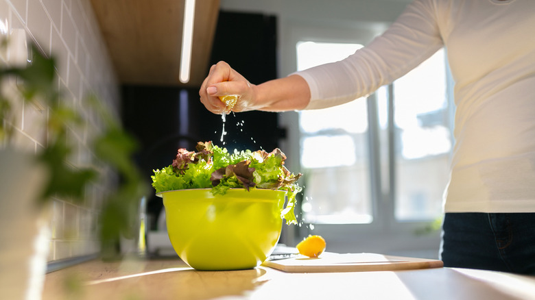 Person squeezing lemon over salad