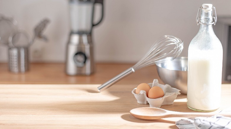 Bottle of milk with eggs and whisk