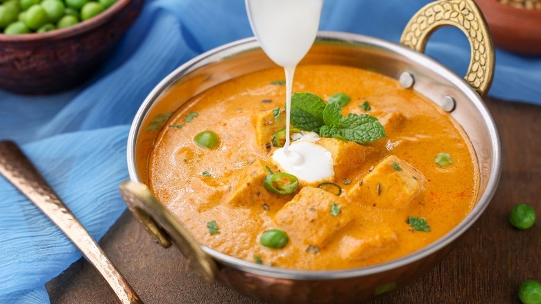 Pouring heavy cream into curry