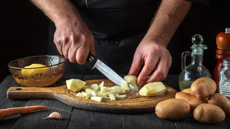person cutting potatoes with knife
