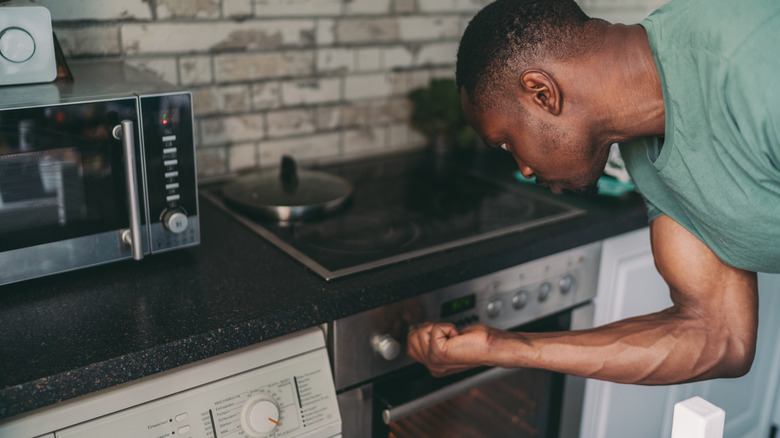 man adjusting oven temperature