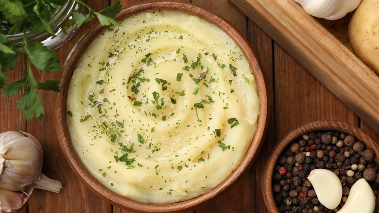 bowl of mashed potatoes surrounded by garlic