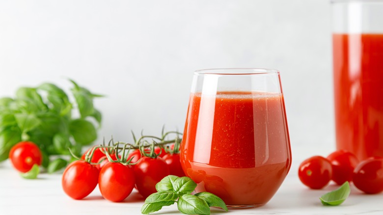 Tomato juice in glass and fresh tomatoes