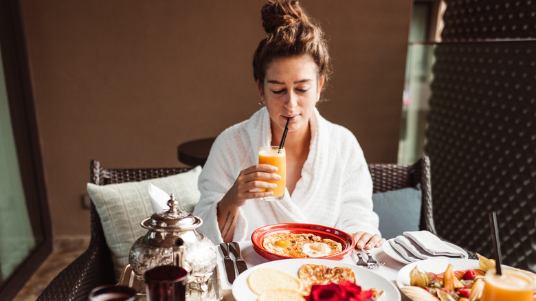 Woman drinking orange juice wearing robe