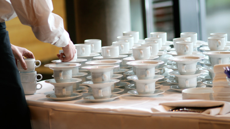 Waiter stacking coffee cups and dishes