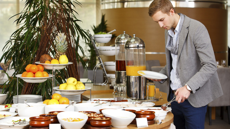 Man taking food from buffet tray