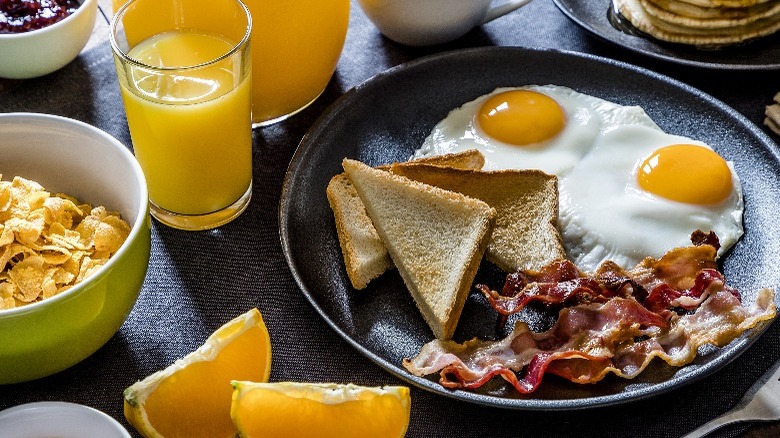 Fried eggs, bacon, toast, OJ on table