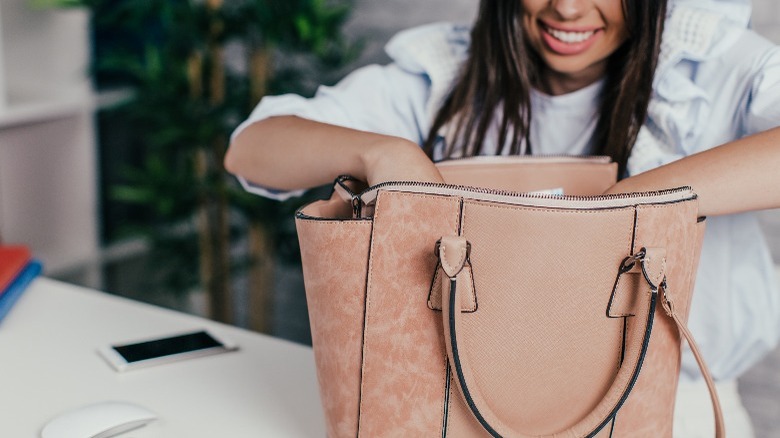 Happy woman reaching into large handbag