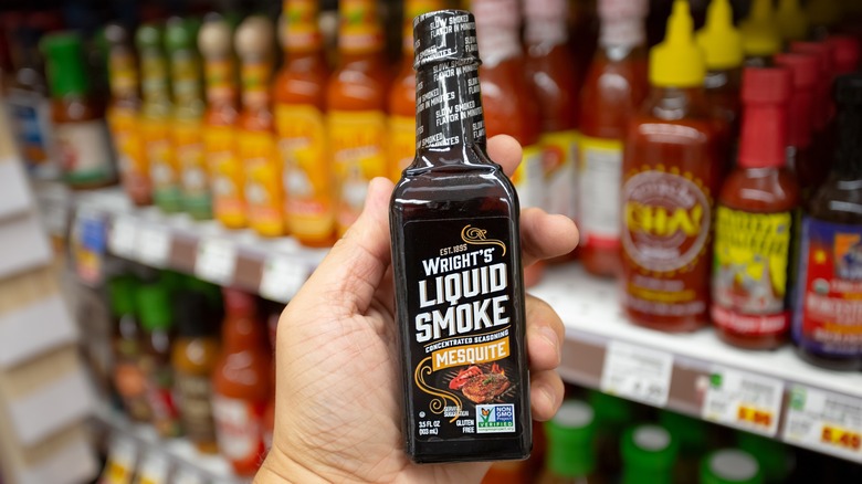 Person holding liquid smoke bottle