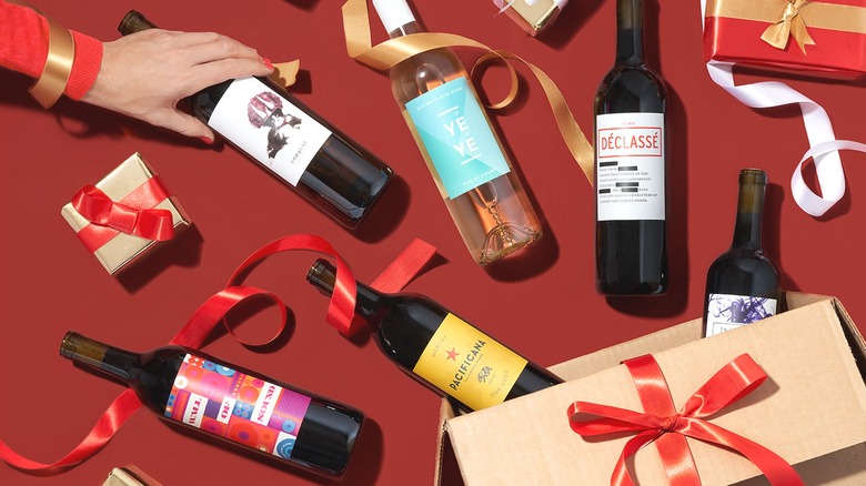 Bottles of wine and gift box with red ribbon on red background